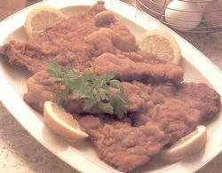 Costillas de ternera empanadas con queso y pan.